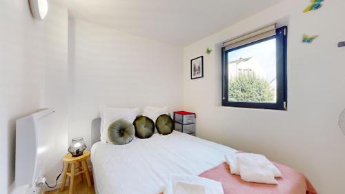 une chambre avec un lit blanc avec une fenêtre dans l'établissement Le Charme Colmarien - Appartement 2 pièces au cœur de la ville, à Colmar
