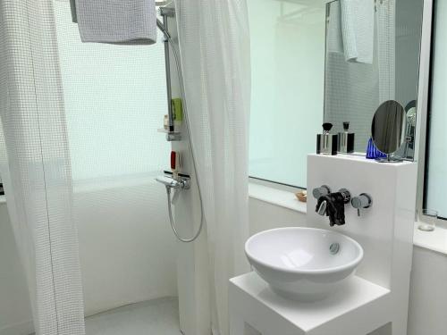 une salle de bain blanche avec un lavabo et une douche dans l'établissement Villa plain-pied, jardin, vélos et kayaks, à 370m de la plage à Landrellec. - FR-1-368-346, à Pleumeur-Bodou