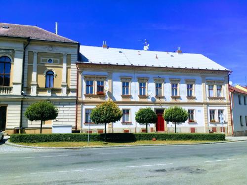 a large white building with trees in front of it at Apartman na namesti in Opočno