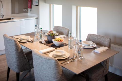 a dining room table with chairs and a wooden table with food on it at Beech House - Urban Apartments in Bristol