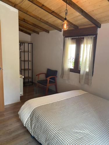 a bedroom with a bed and a chair and a window at Vivienda Vacacional La Quesería in Oceño