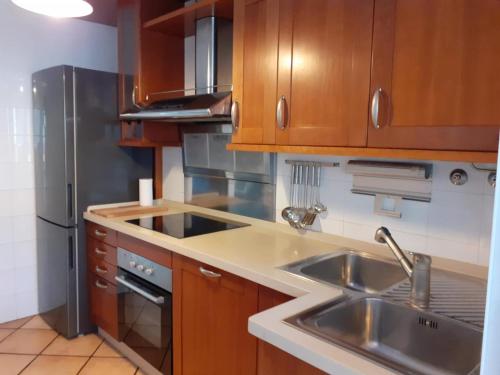 Una cocina con gabinetes de madera y un refrigerador de acero inoxidable. en La casa familiar, en Puerto Real