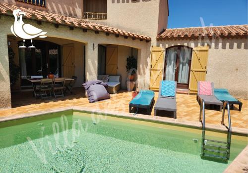 une maison dotée d'une piscine avec deux chaises et une table dans l'établissement La villa des goélands, au Barcarès