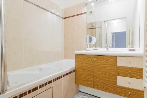 une salle de bain avec une baignoire, un lavabo et un miroir dans l'établissement Classy appartement - Clichy, à Clichy