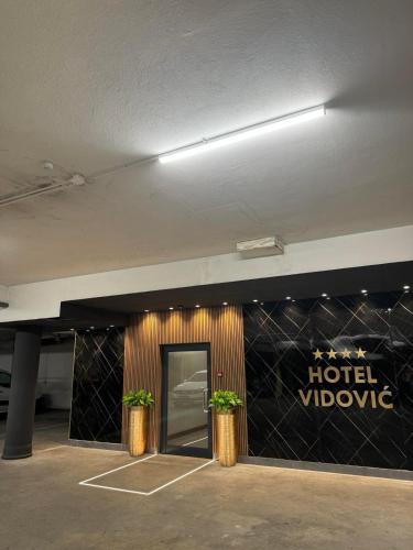 a hotel doorway with two potted plants in front of it at Hotel Vidović in Banja Luka