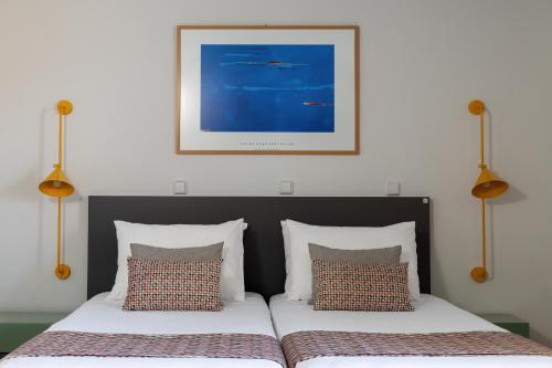 a bedroom with two beds and a picture on the wall at Flisvos Royal Hotel & Suites in Tolo