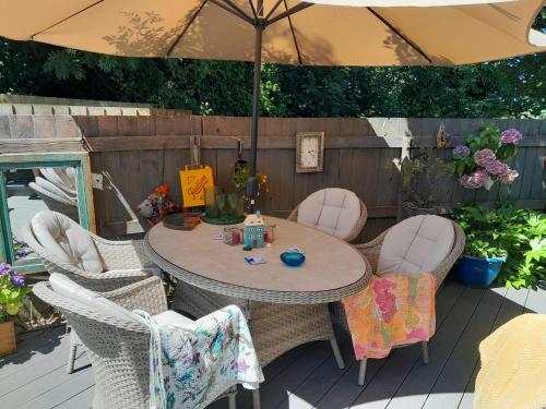a table and chairs with an umbrella on a deck at Sailaway in Carbis Bay