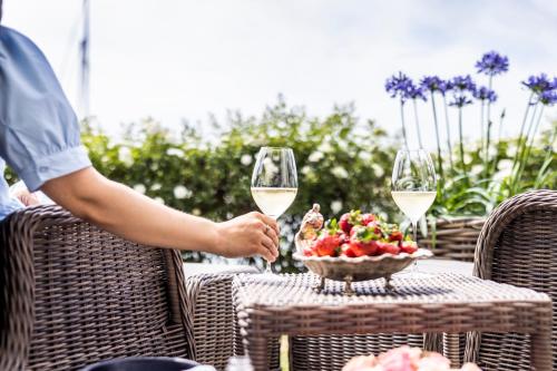 a table with two glasses of wine and a bowl of fruit at Dyvig Badehotel in Nordborg