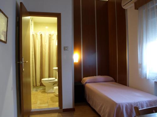 a bedroom with a bed and a toilet and a mirror at Hostal Anas in Merida