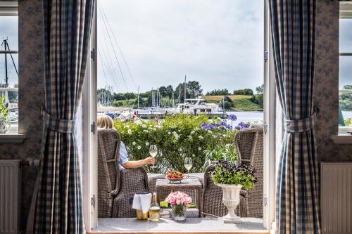a woman sitting on a porch with a glass of wine at Dyvig Badehotel in Nordborg