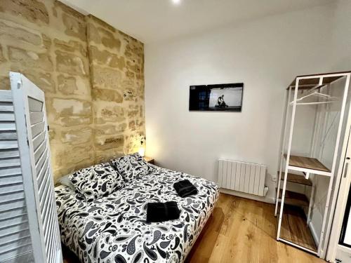 une chambre avec un lit et un mur en pierre dans l'établissement Petit loft en centre historique, à Bordeaux