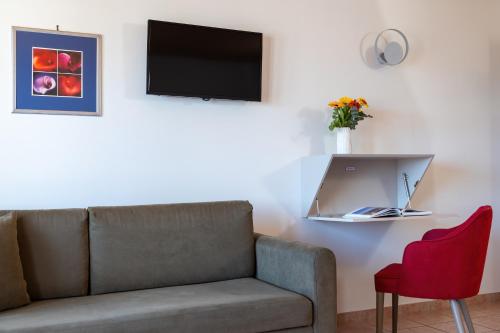 a living room with a couch and a tv at Flisvos Royal Hotel & Suites in Tolo