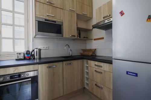 une cuisine avec des armoires en bois et un réfrigérateur blanc dans l'établissement Exceptional apt - 2BR-4P- Notre-Dame Cathedral, à Paris