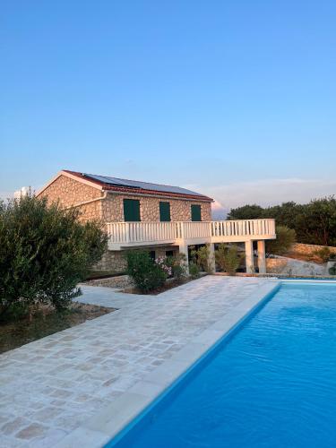 a swimming pool with a bench next to a house at Villa Maslina in Novalja