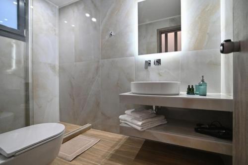 a bathroom with a toilet and a sink and a mirror at TRES V Suites & Apartments in Stavros