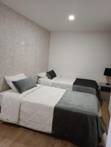 two beds in a room with white walls at HERMOSO y CÓMODO APARTAESTUDIO SABANETA in Sabaneta