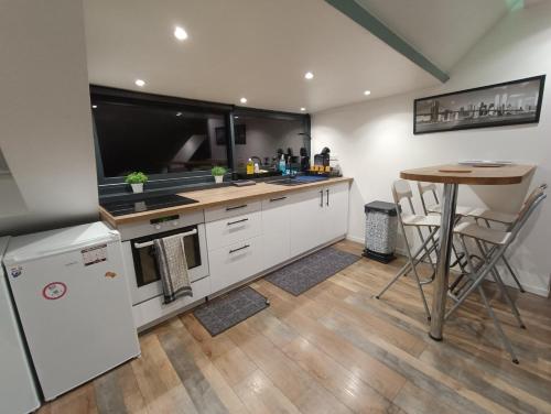 une cuisine avec des placards blancs, une table et un comptoir dans l'établissement Appartement de charme centre ville, à Rouen