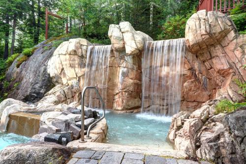 une cascade dans une piscine d'eau avec des rochers dans l'établissement Tremblant Prestige - Les Eaux 223-4, à Mont-Tremblant