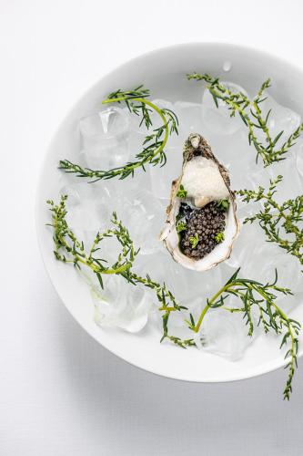 a oyster on a white plate with green herbs at Dyvig Badehotel in Nordborg