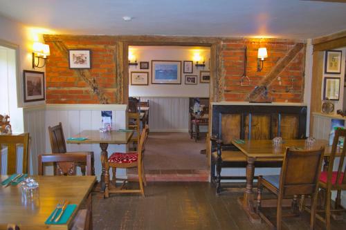a restaurant with tables and chairs and a brick wall at the Cartwheel Inn in Whitsbury