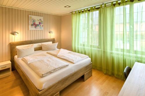 a bedroom with a large bed with green curtains at Hotel Sonne in Staufen im Breisgau