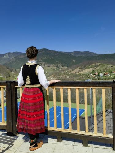 a woman standing on a balcony looking at the mountains at Mecavnik Resort in Mokra Gora
