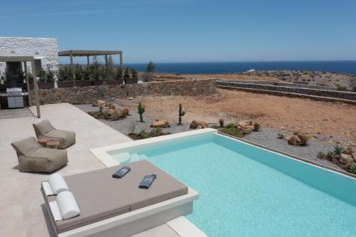 a swimming pool with a couch and chairs and the ocean at Onos Luxury Villas Kythnos in Kithnos