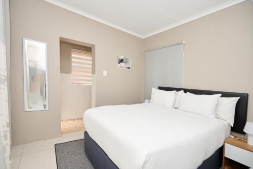 a white bedroom with a large white bed in it at Sunny villa with pool and garden in Pretoria