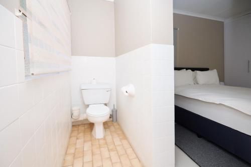 a small bathroom with a toilet and a bed at Sunny villa with pool and garden in Pretoria