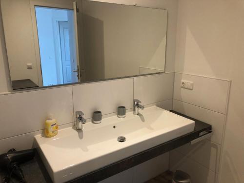 a bathroom with a white sink and a mirror at "Sonne auf der Haut" - Residenz Glücksmomente 1OG in Langeoog