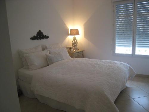 - une chambre dotée d'un lit blanc avec une lampe et une fenêtre dans l'établissement Beachside apartment with sea view, à Antibes