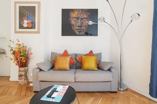 - un salon avec un canapé gris et des oreillers colorés dans l'établissement Luxe 1-BR Gem Louvre & Opera, à Paris