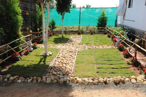 a garden with rocks and a walkway next to the water at Tigerwoods Cottage in Chikmagalūr