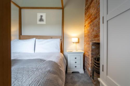 ein Schlafzimmer mit einem Bett und einem Kamin in der Unterkunft Willow Cottage SC in South Creake