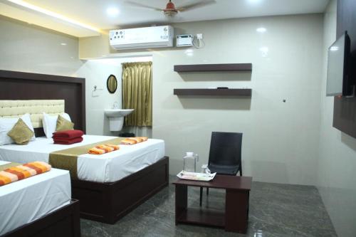 a hotel room with two beds and a table at Hotel Temple Tower in Rāmeswaram