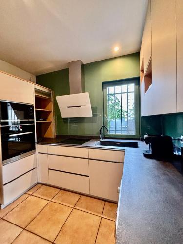 une cuisine avec des placards blancs et une grande fenêtre dans l'établissement Grande Maison Clermont Ferrand, à Clermont-Ferrand