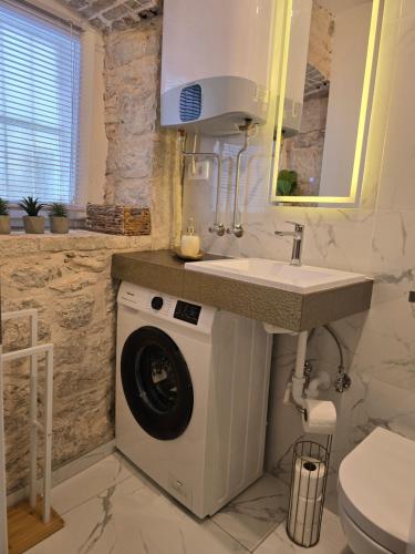 a bathroom with a washing machine under a sink at Apartment Rose Cres 4 in Cres