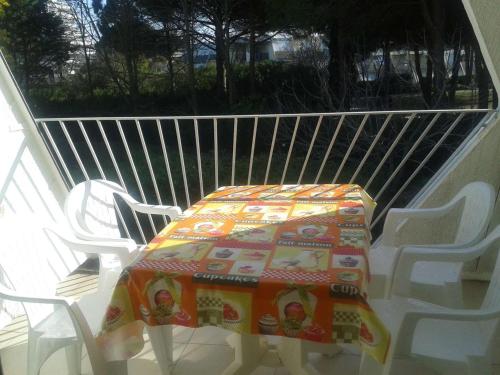 une table et des chaises sur un porche avec une couverture dessus dans l'établissement Studio Calme avec Loggia, à 600m de la Plage et Proche Commerces - FR-1-328-93, à La Grande Motte