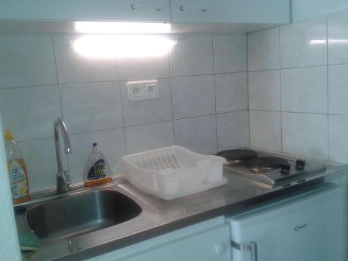 un évier de cuisine avec une passoire sur le comptoir dans l'établissement Studio Calme avec Loggia, à 600m de la Plage et Proche Commerces - FR-1-328-93, à La Grande Motte