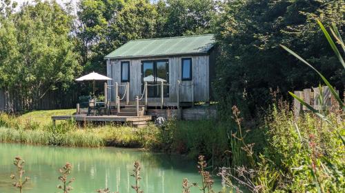 a tiny house sitting on the side of a pond at Lynstone Lakes in Bude