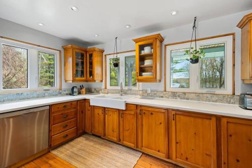 a large kitchen with wooden cabinets and windows at Marmora Retreat - Unique Waterfront Farmhouse in Marmora