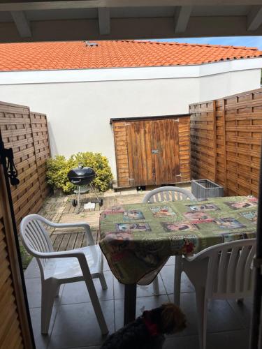 - une table avec deux chaises et un chien assis dans l'établissement Chapelle, à Mimizan-Plage