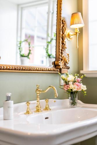 a bathroom sink with a mirror and a vase of flowers at Dyvig Badehotel in Nordborg