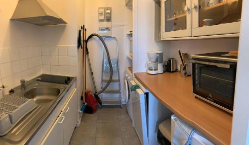 une petite cuisine avec un évier et un micro-ondes dans l'établissement La frégate marine de St Hilaire, à La Parée Preneau