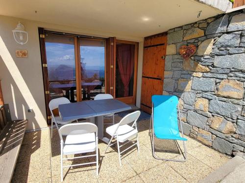 une table et des chaises sur une terrasse avec un mur en pierre dans l'établissement Appartement lumineux 5 pers avec terrasse plein Sud à Chaillol 1600 - FR-1-393-78, à Saint-Michel-de-Chaillol