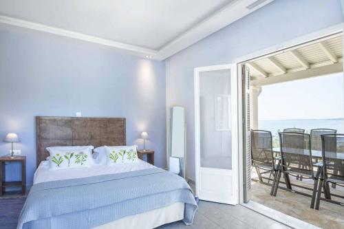 een slaapkamer met een bed en een balkon met uitzicht op de oceaan bij Villa Giovannina in Perama