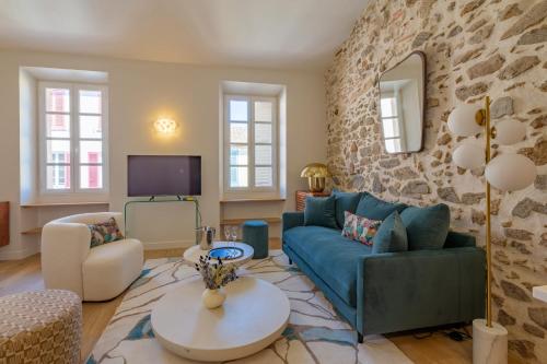 - un salon avec un canapé bleu et un mur en pierre dans l'établissement Appartement Piedras - Welkeys, à Saint-Tropez