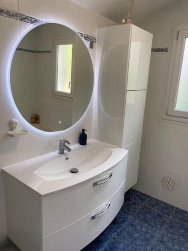une salle de bain blanche avec un lavabo et un miroir dans l'établissement Charmante Maison Familiale près de Paris, à Drancy
