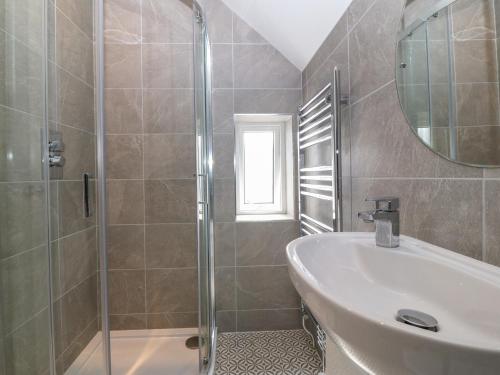 a bathroom with a shower and a sink and a mirror at Elsinore in Conwy