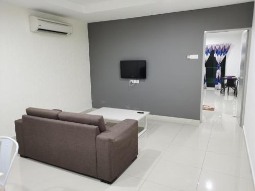 a living room with a couch and a tv on a wall at Marina Island Couple Home Stay in Lumut